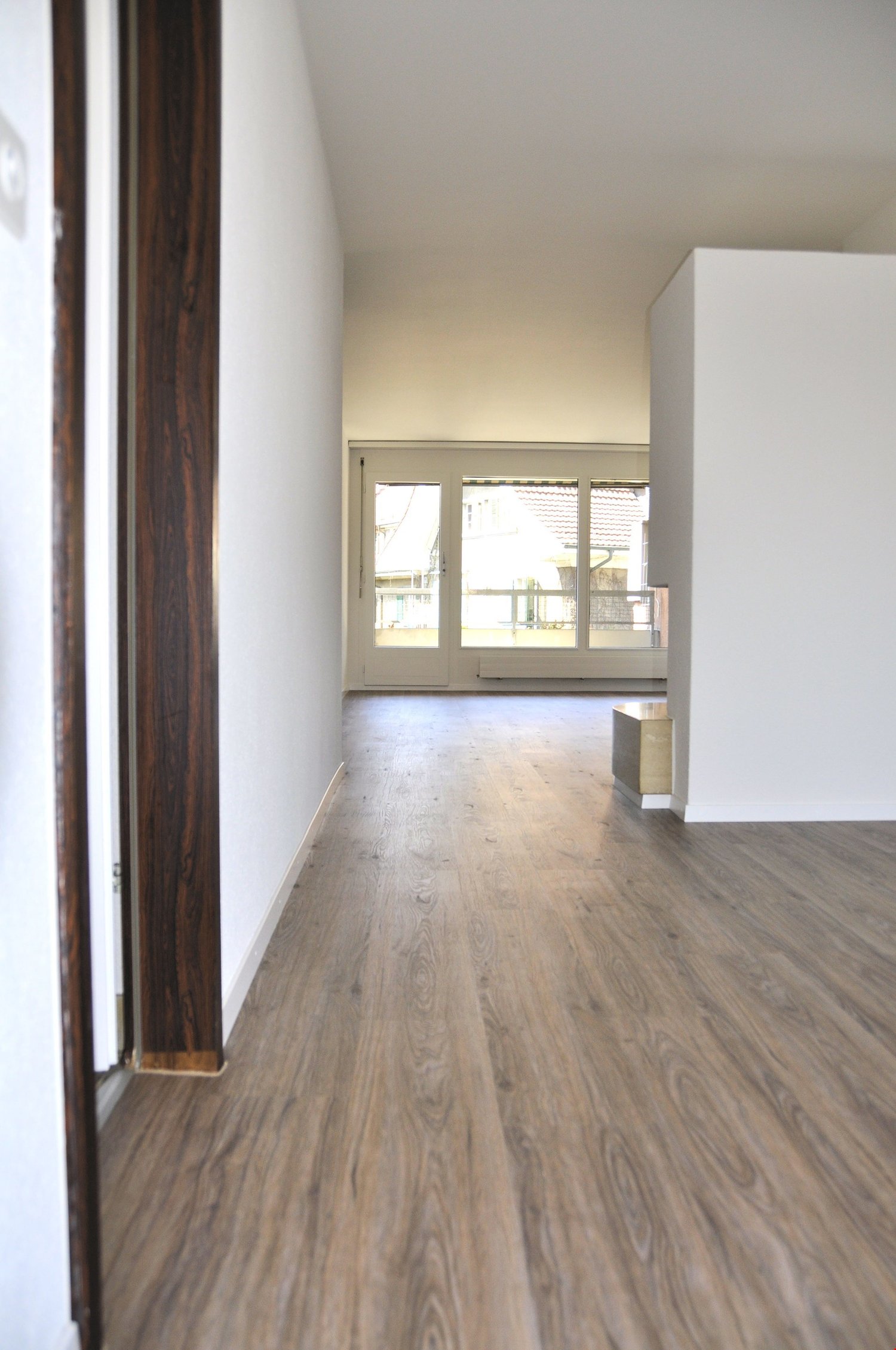 empty room with wooden floor, white walls, glass doors leading to a balcony