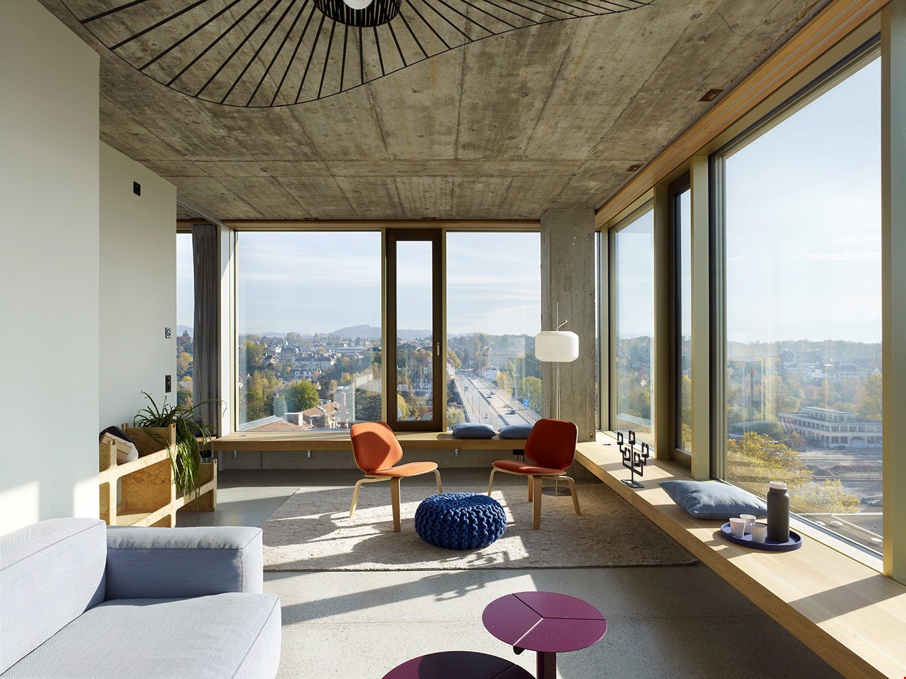 wide view windows, large open space, wooden bench, orange chairs, round table, carpet