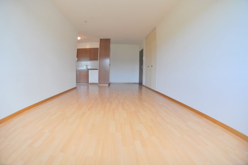 hallway with wood floor, white walls, kitchen cabinets, and closed doors leading to other rooms