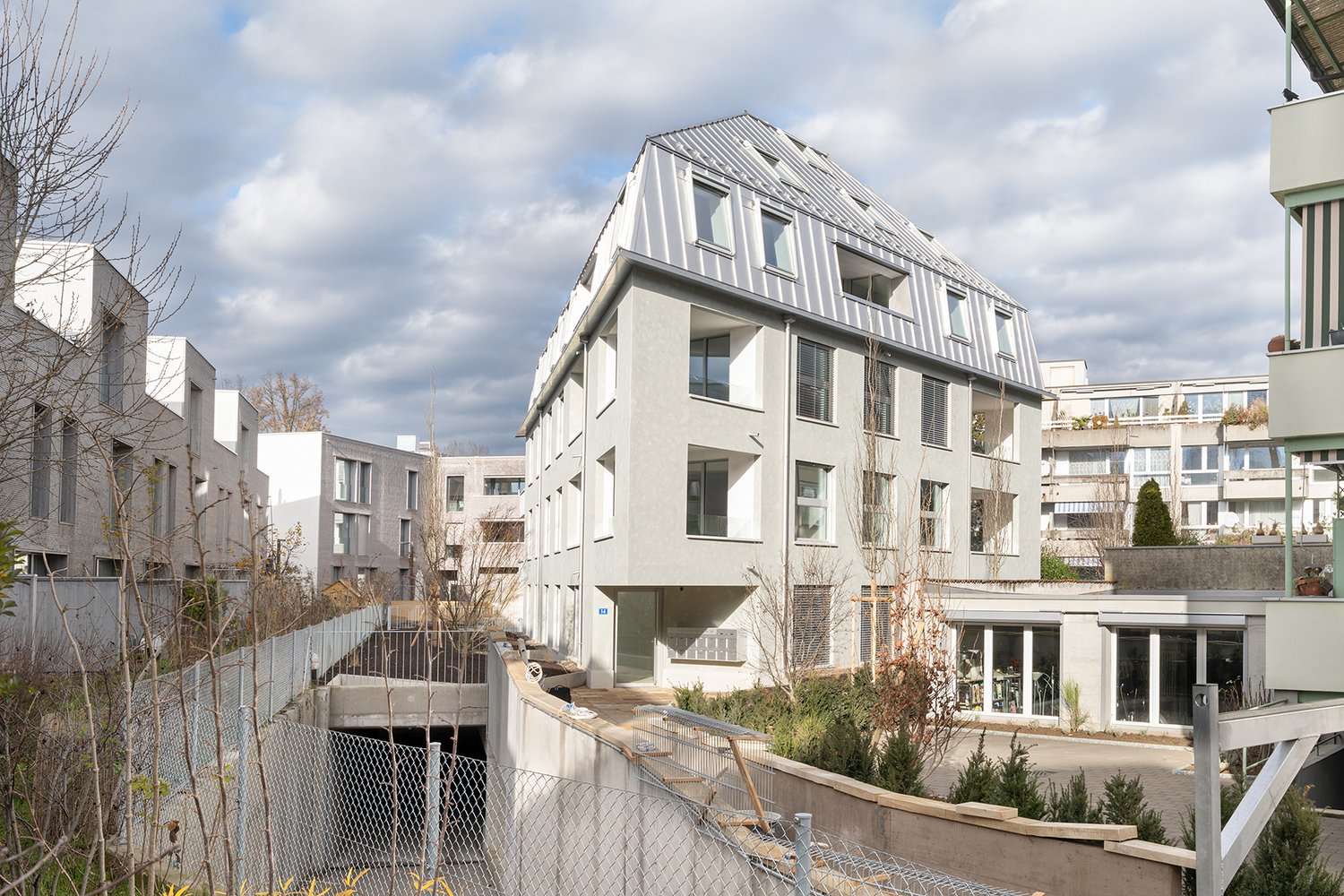 modern building with multiple windows, white exterior, rooftop metal sheet, fenced entrance