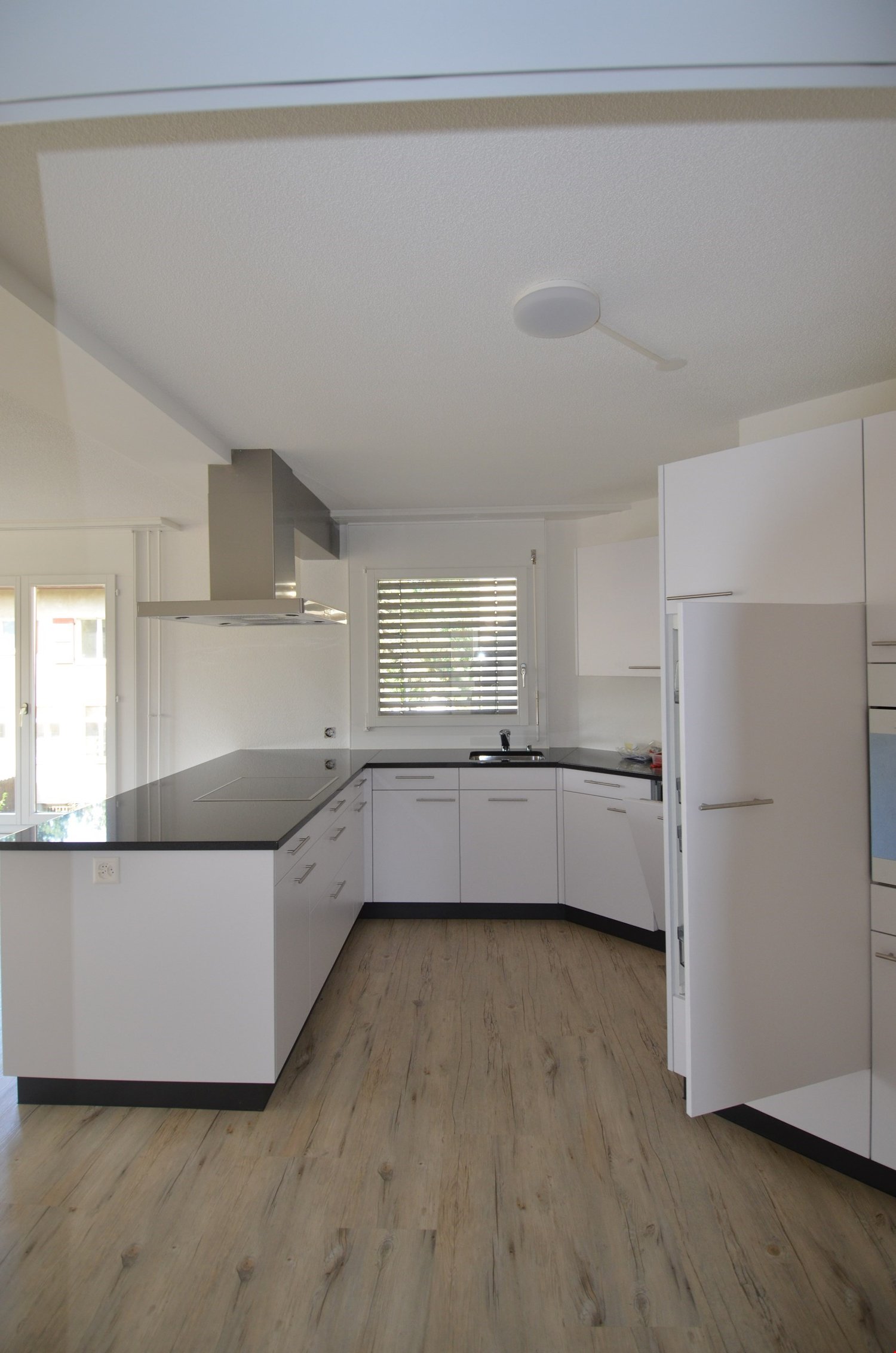 white cabinets, black countertops, gas stove, extractor hood, dishwasher, refrigerator, power outlet