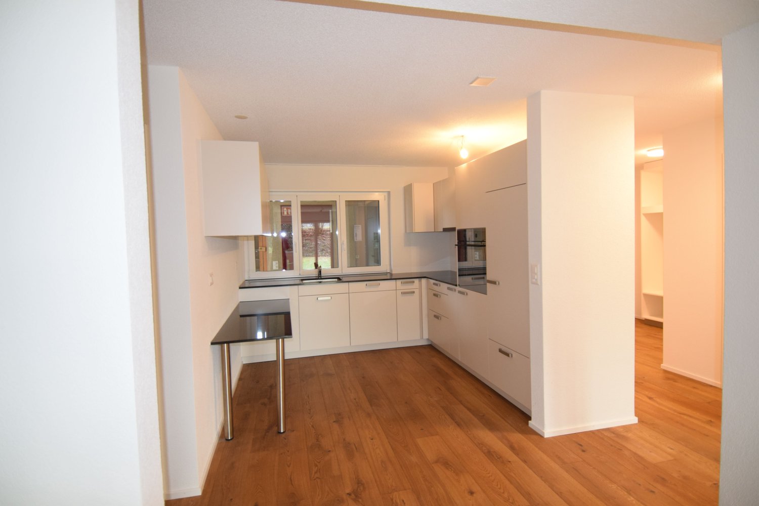 modern kitchen with white cabinetry, wooden flooring, countertop, window, stainless steel oven