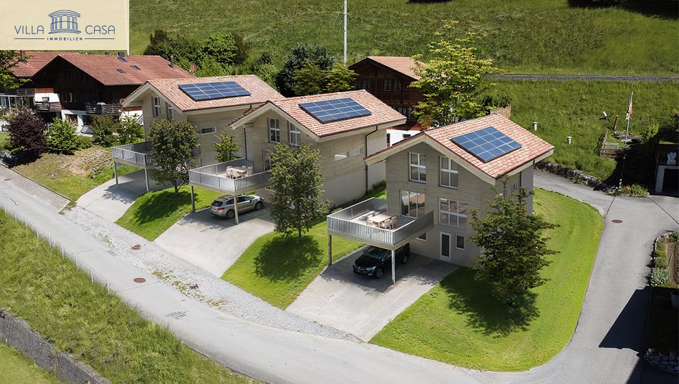 two townhouses, each with a carport and terrace, solar panels on the roofs, green lawn, garden area