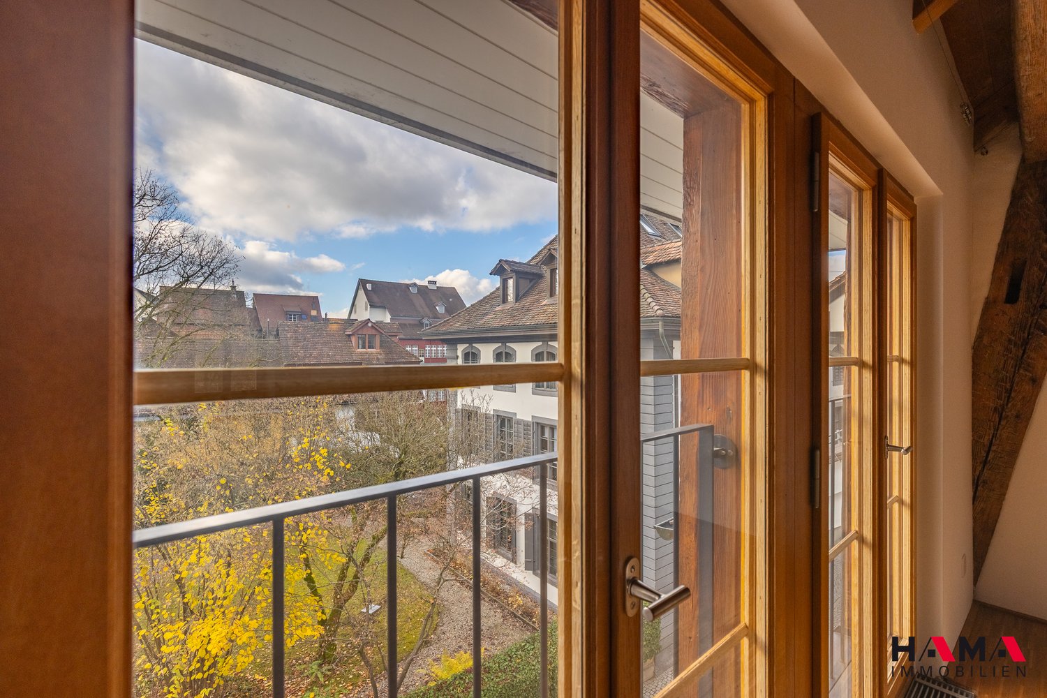 large window, balcony with railing, view of the cityscape
