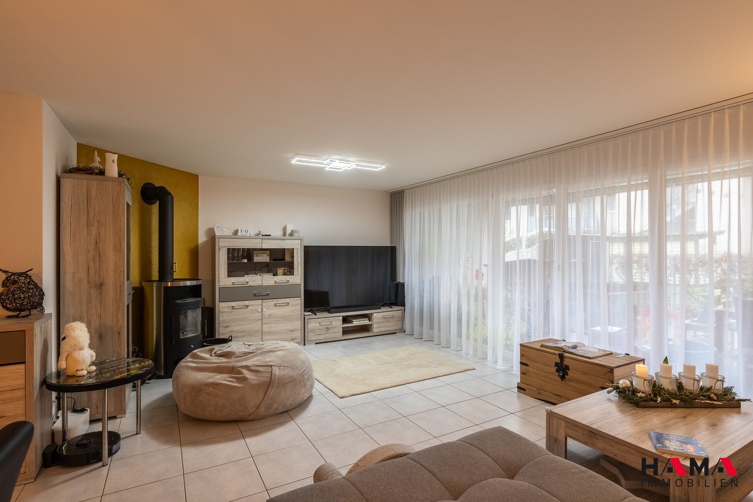 tiled floor, beige carpet, sofa, large windows, television, coffee table, side tables