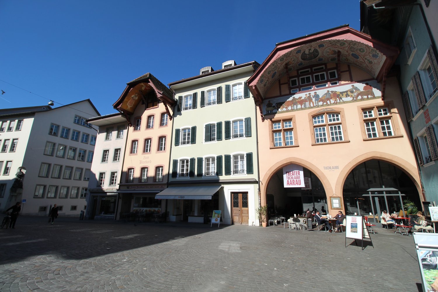 Multi-story building, brick walls, arched windows, wooden door, awning, street scene