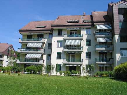 3 story building, balconies on each floor, large lawn in front