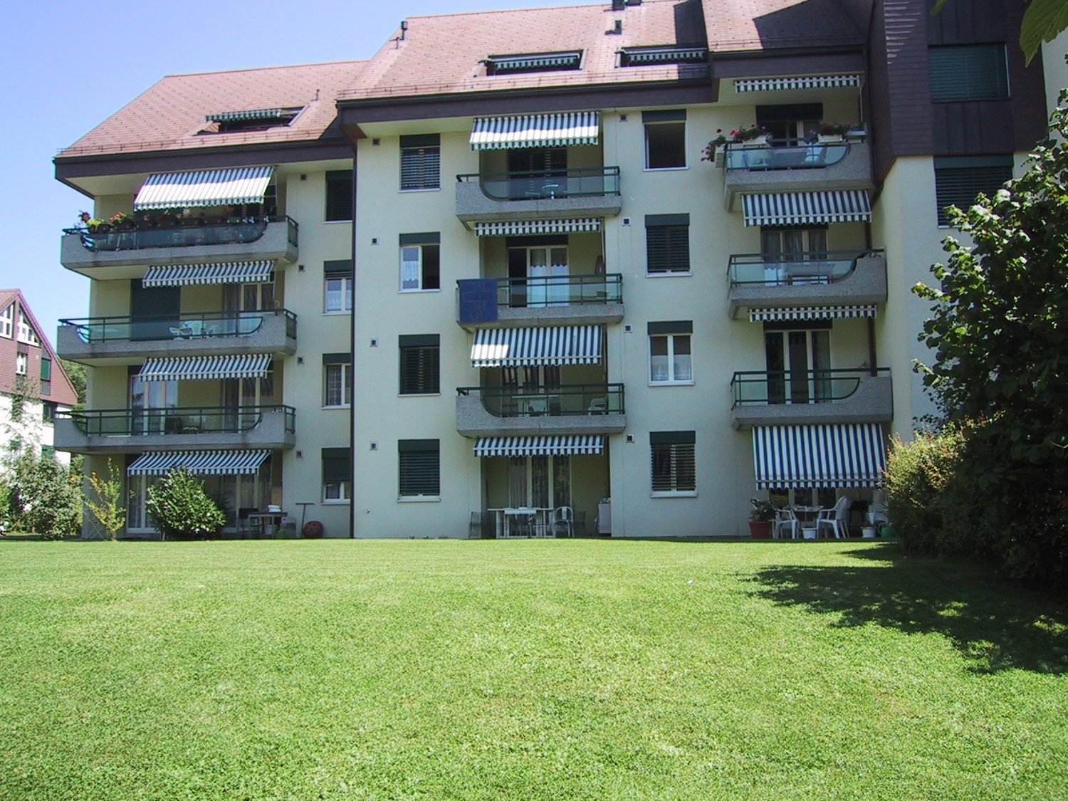 4 story apartment building, many balconies, wide lawn in front of the building
