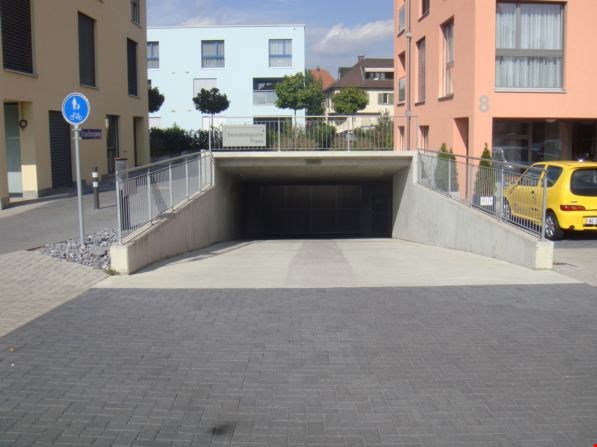 Underground parking lot with a ramp, metal railings, and a yellow car parked outside