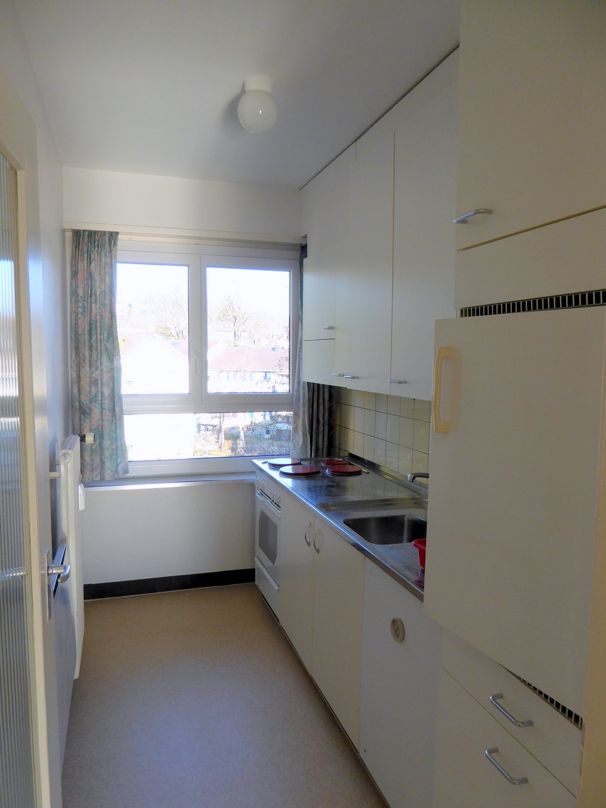 Clean modern kitchen with modern cabinets, white walls, and appliances including fridge, stove, and sink.