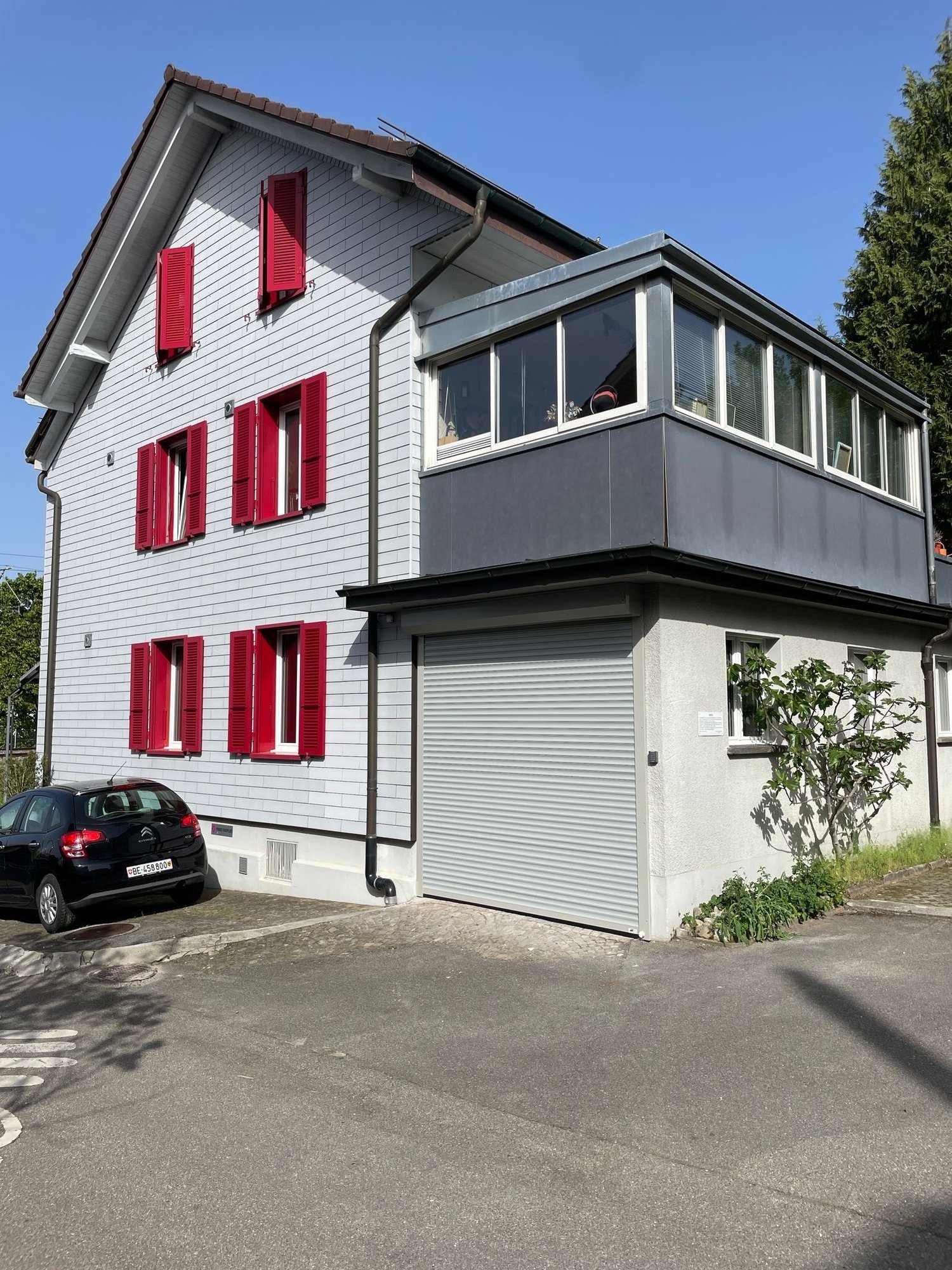 2 story house, red shutters, white exterior, garage, black car parked