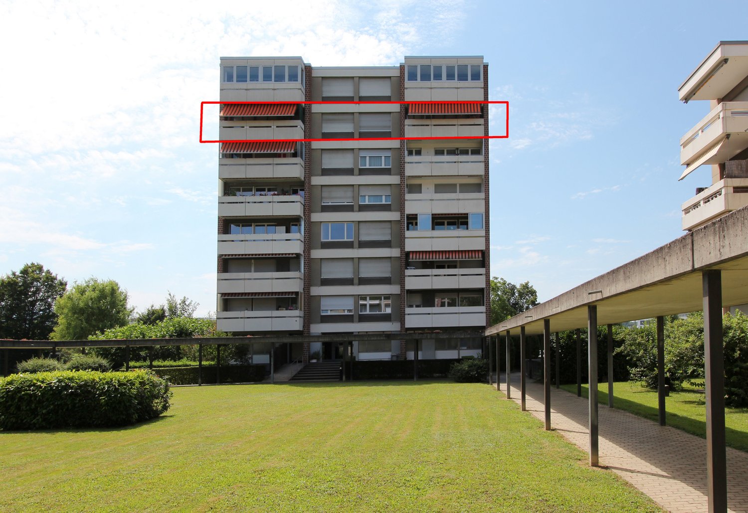 Apartment building, multiple balconies, brick exterior, two floors, surrounded by a landscaped lawn