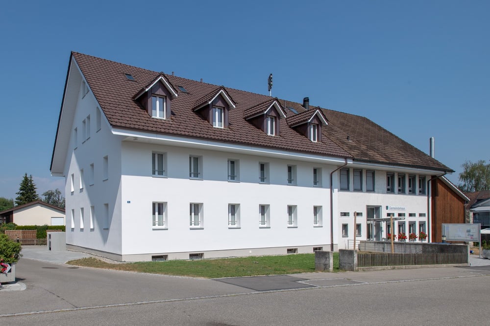 Two story house, white walls, brown roof, large windows