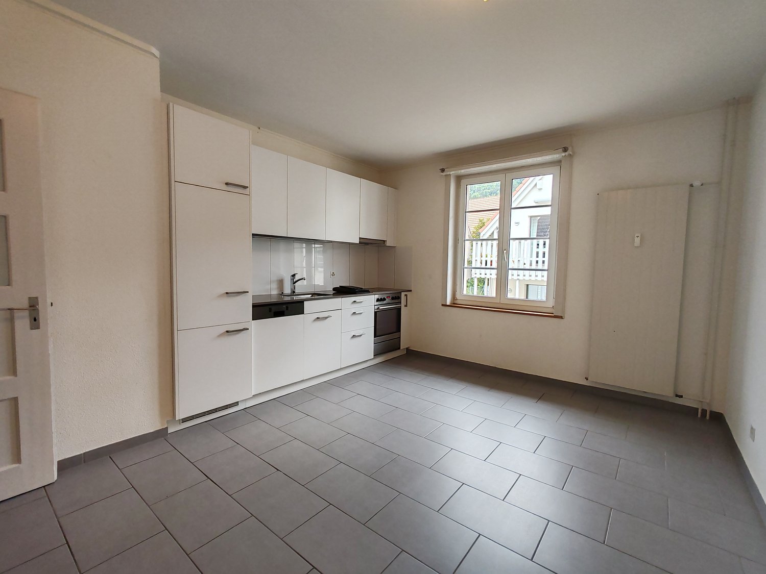 White cabinets, grey tiled floor, sink, faucet, oven, dishwasher, dishwasher, window with view