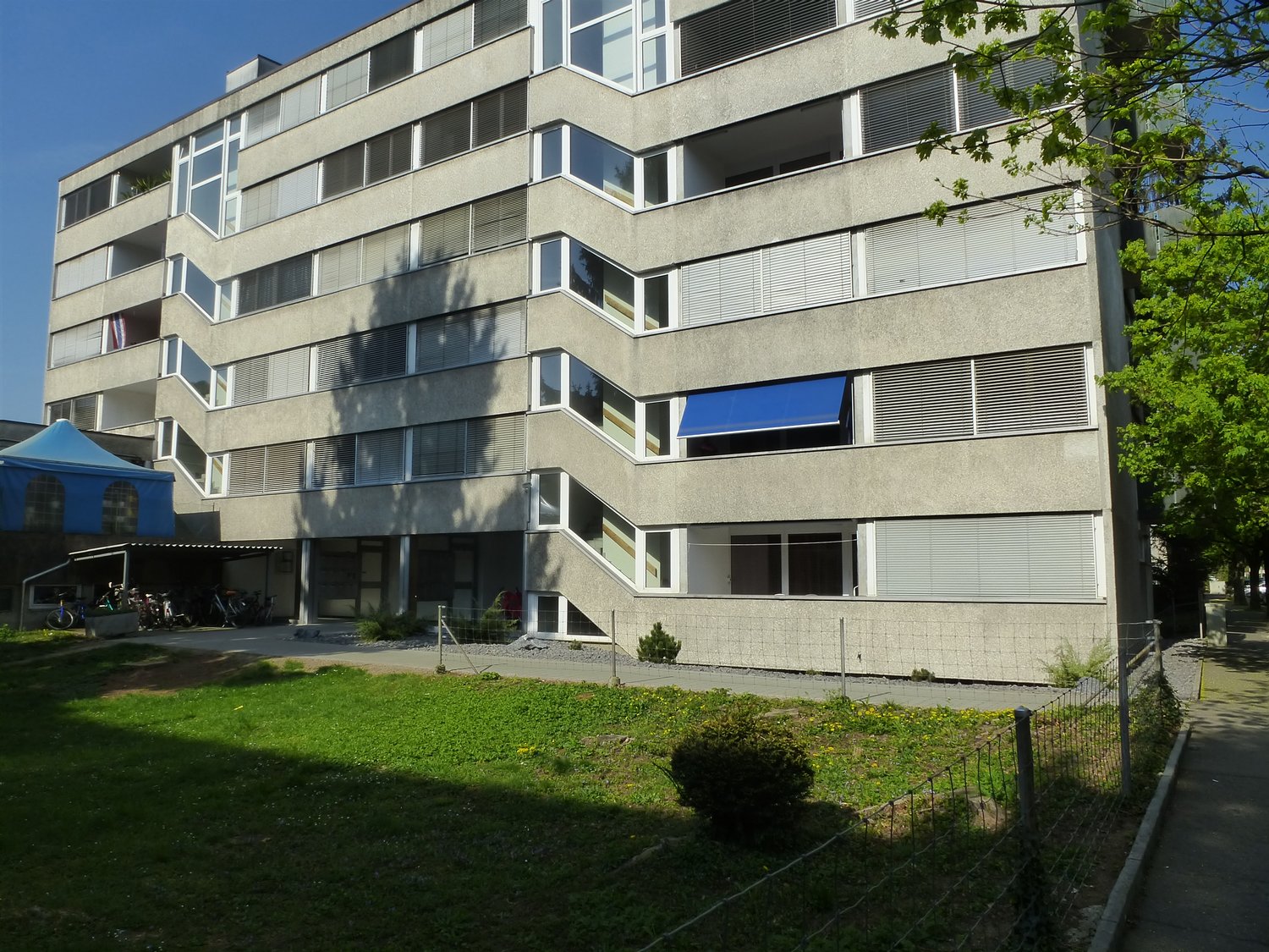 Modern apartment building, many windows, terrace, outdoor area, parking, entrance area, bicycles parked