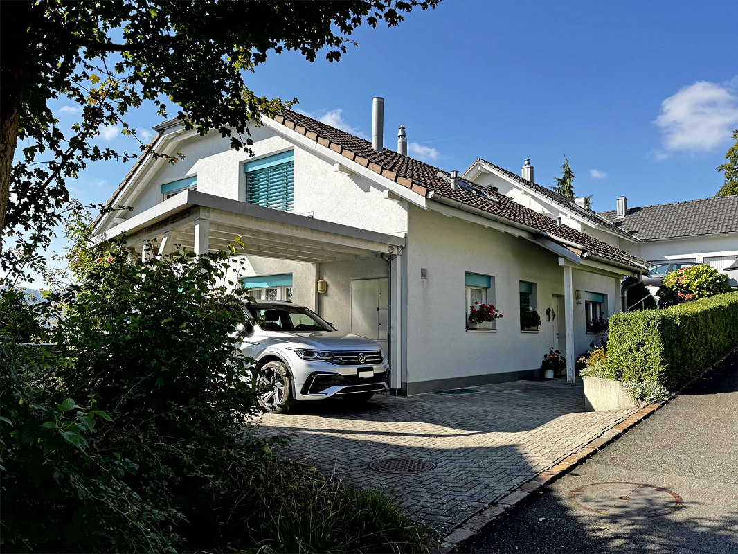 Single family house, white facade, brown roof, attached garage, garden, shrubs, silver SUV parked in the garage