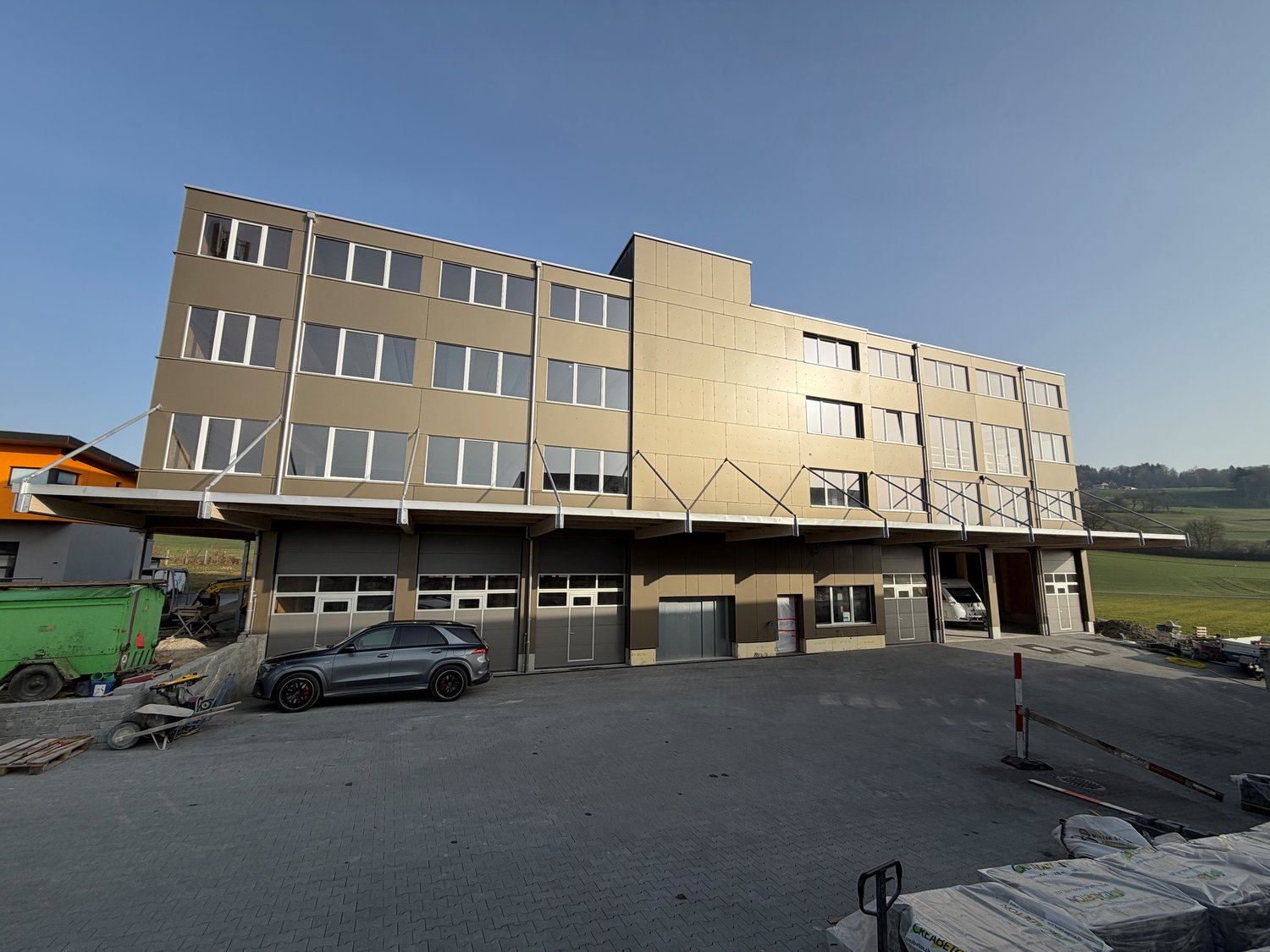 4 story building, brown exterior, multiple windows, garage, car parked in front