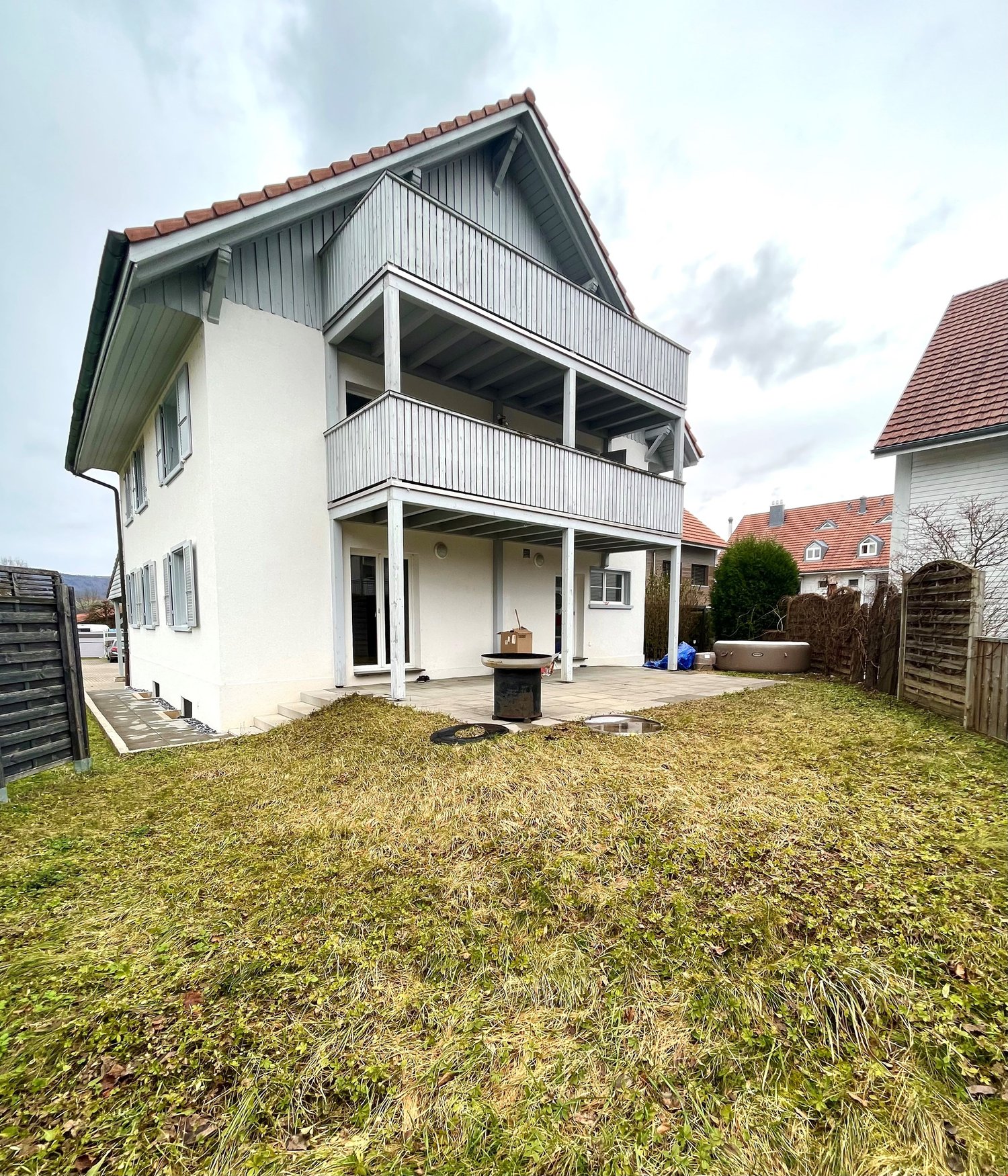 2 story house, white exterior, large balcony, paved patio, fenced yard