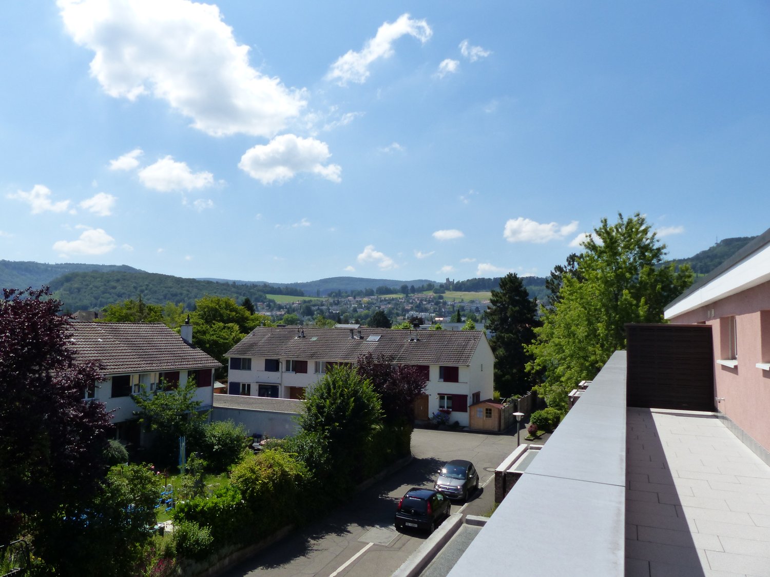 Houses, parking area with 2 cars, trees, balcony