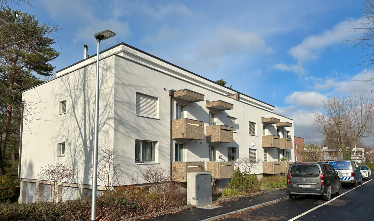 modern, white, 3-story building with multiple balconies, modern street light, parking area with several parked cars