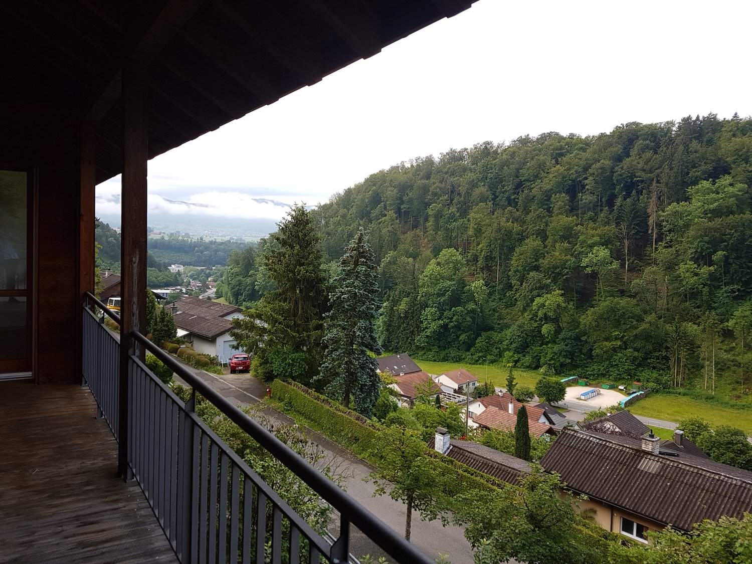 wooden floor, wooden railing, glass door, outdoor balcony, view of greenery, road