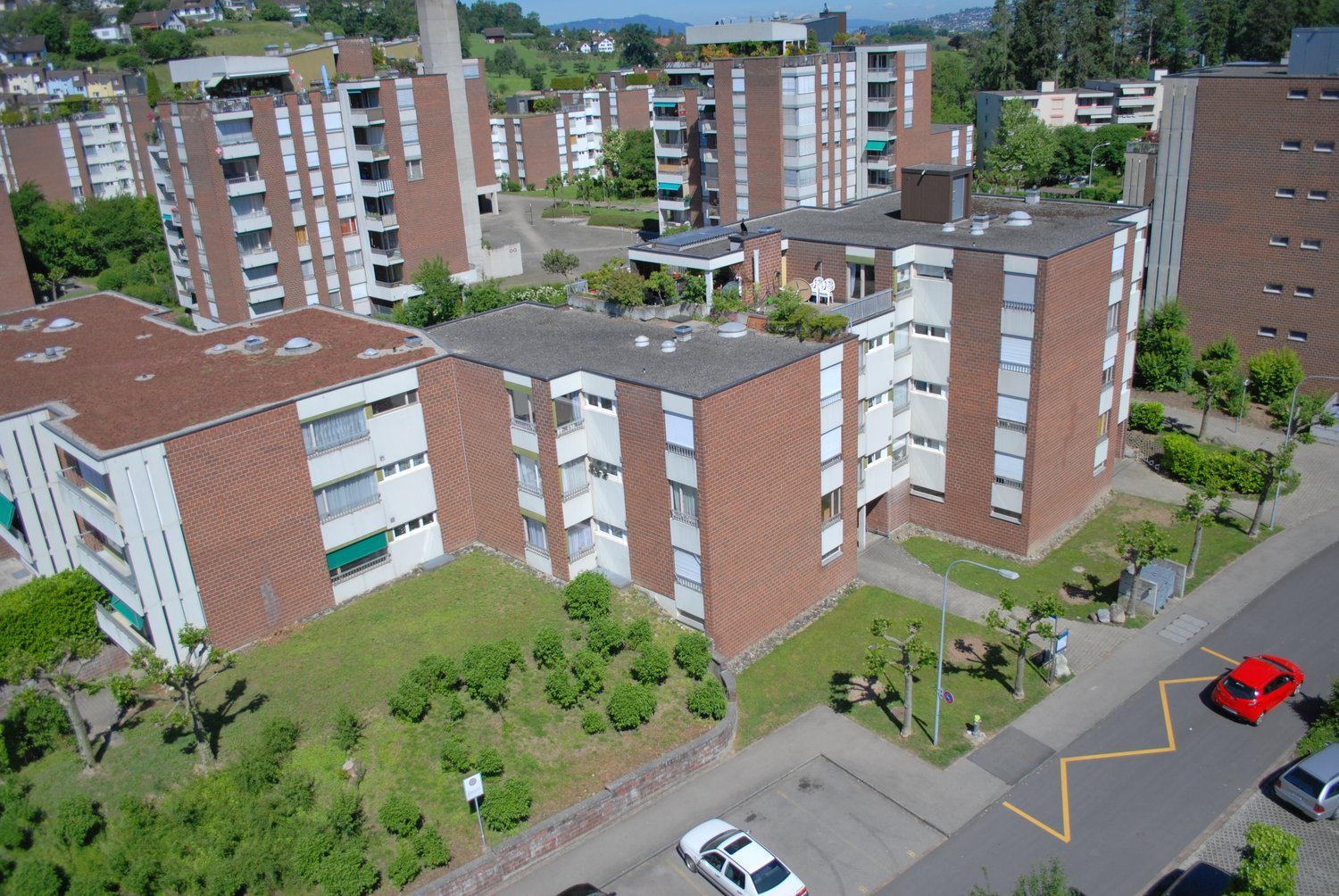 Multi-story apartment buildings, brick exterior, common outdoor area, street, parking