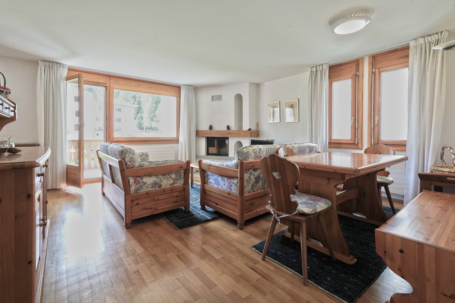 wooden furniture, wooden flooring, balcony access, fireplace, large windows, dining table and chairs