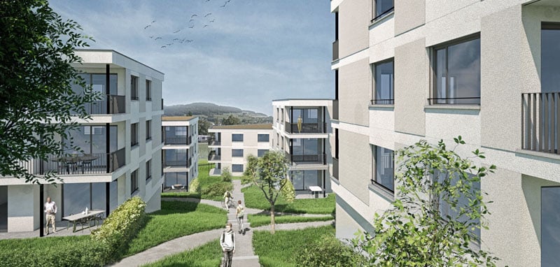 Multi-story apartment building with balconies, surrounded by greenery and landscaping, with a walkway leading through the grounds