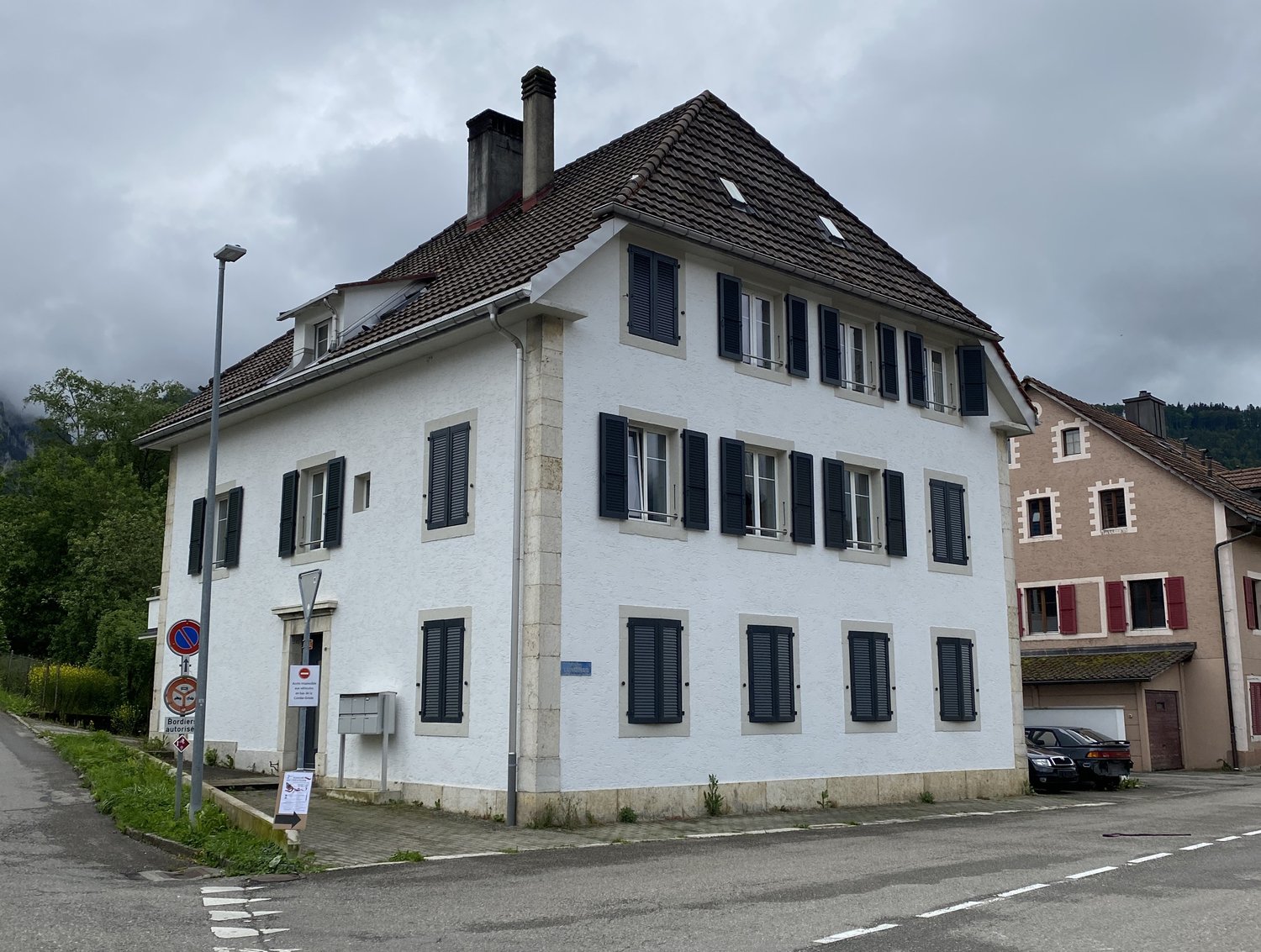 3 story house, white walls, brown roof, black shutters, chimney, 2 cars parked in front