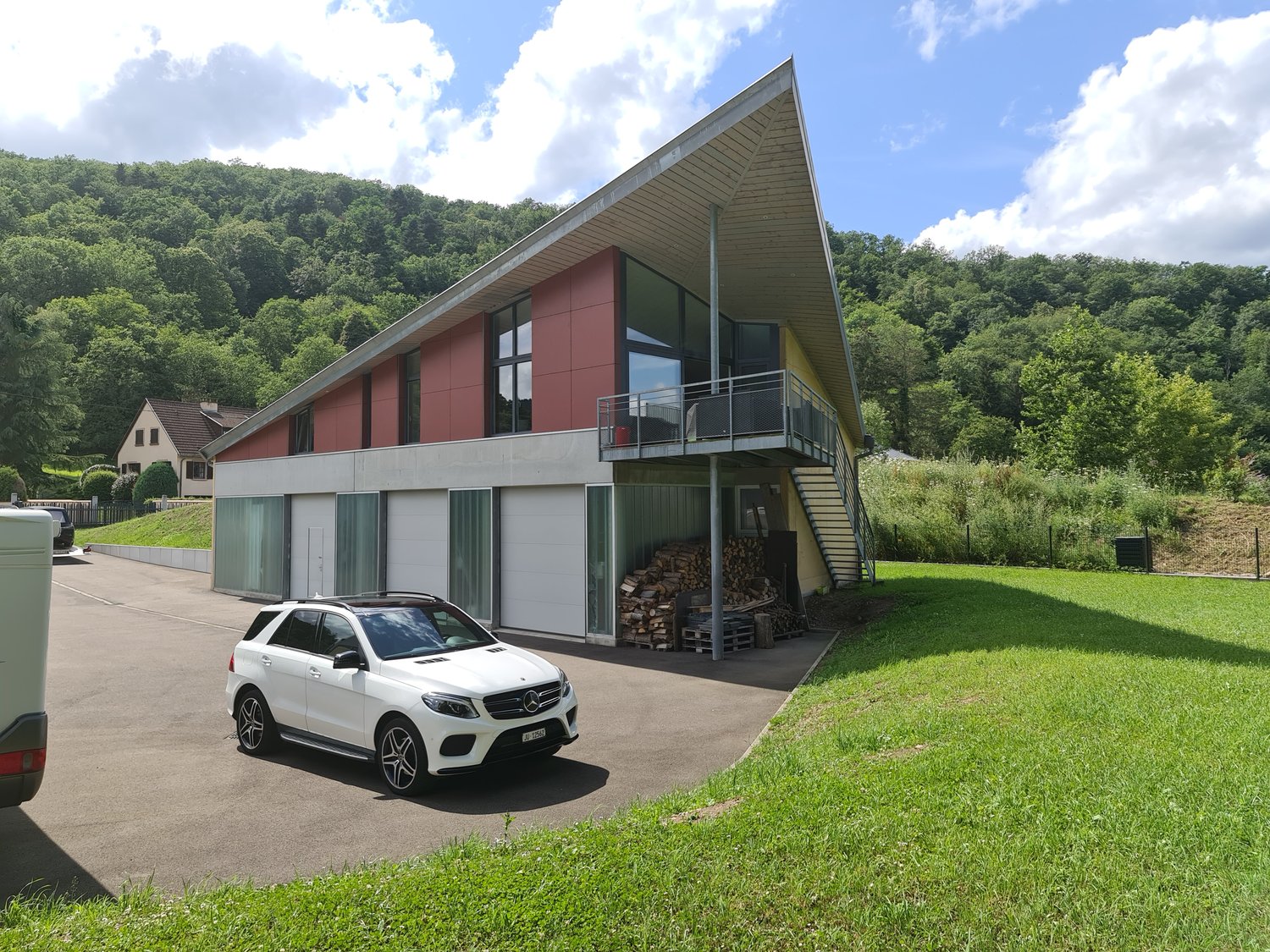 modern house, red wall, gray roof, glass windows, garage, large driveway, green grass, white car