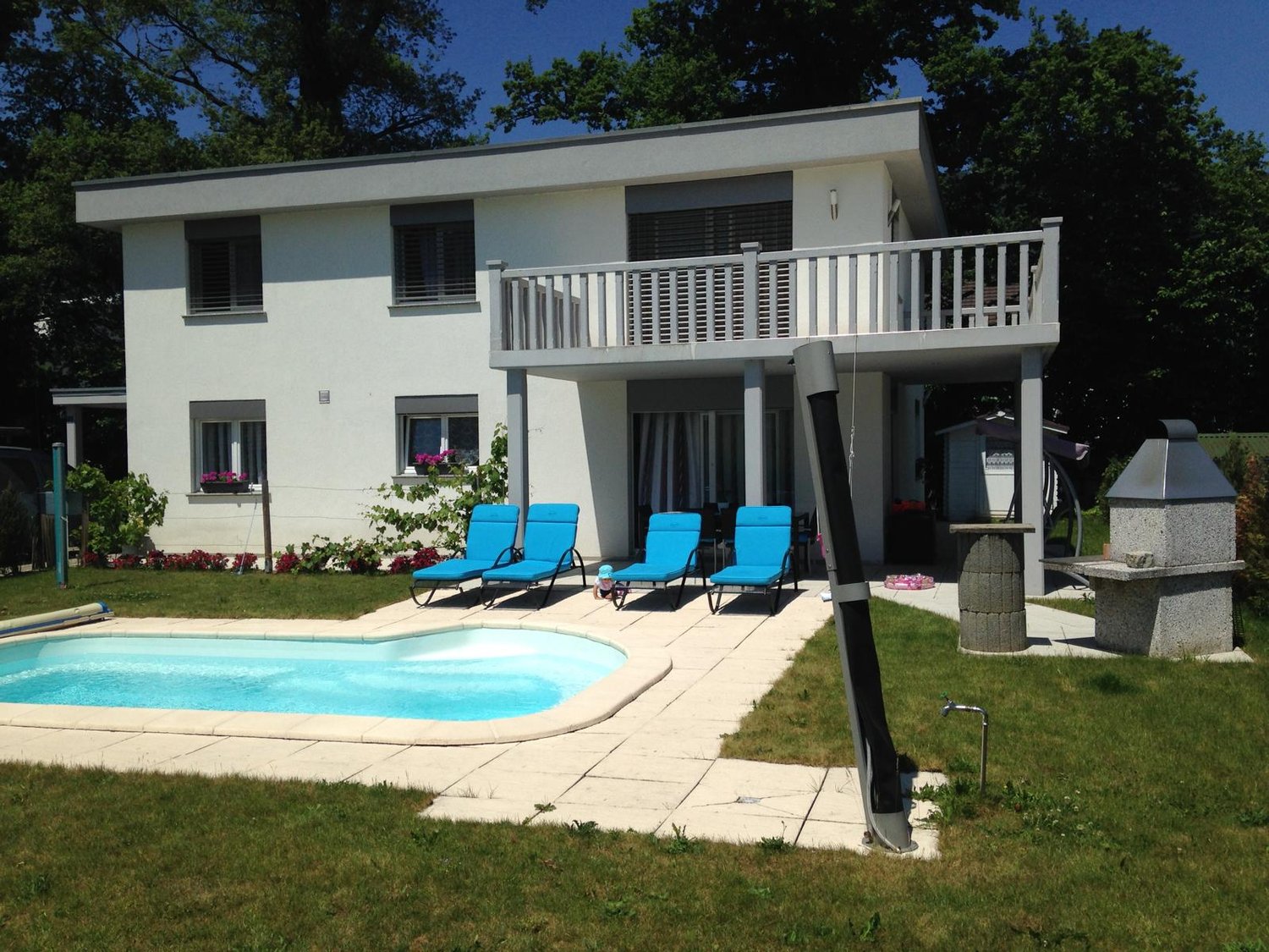 modern white house, with balcony, 3 lounge chairs, swimming pool, grass, flower beds