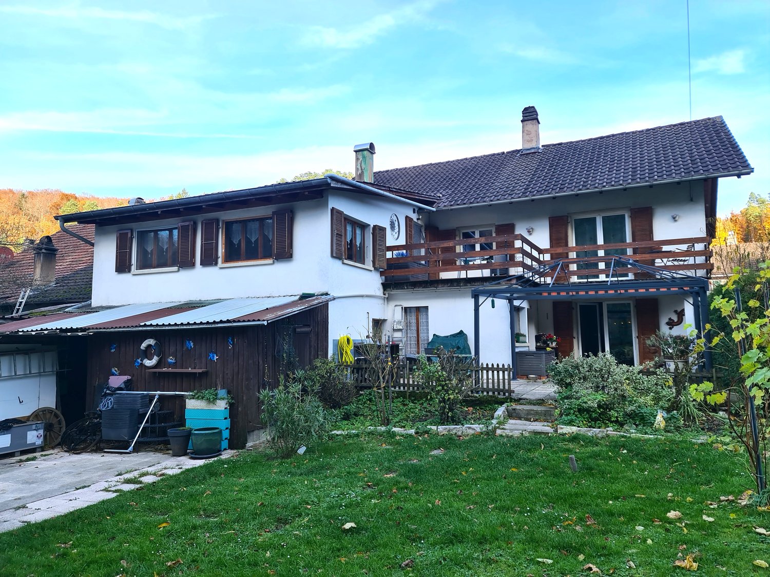 White house, brown roof, balcony, large front yard, attached wooden garage, chimney