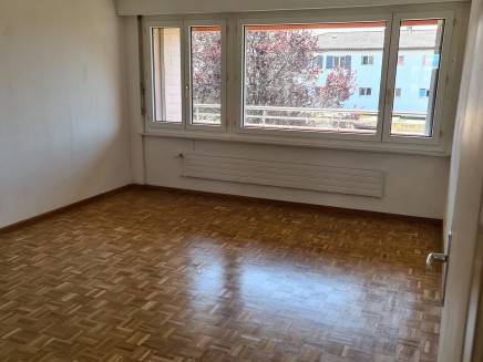 Spacious living room with large windows, hardwood flooring, and access to a balcony or terrace.