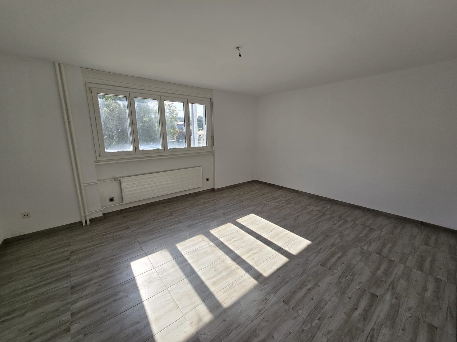 empty room, white walls, wooden floor, large window, heater