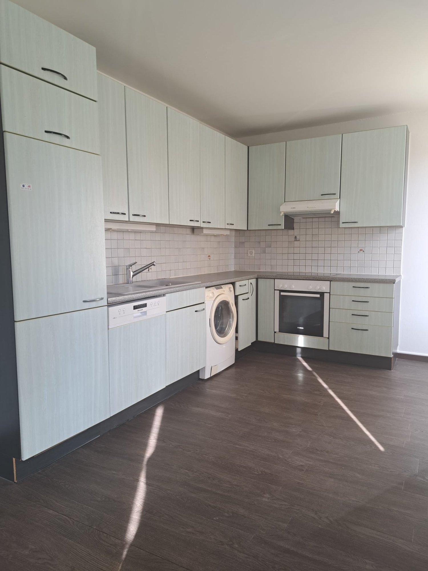 Modern kitchen with wooden cabinets, granite countertops, integrated dishwasher and washing machine, stainless steel appliances, tiled backsplash