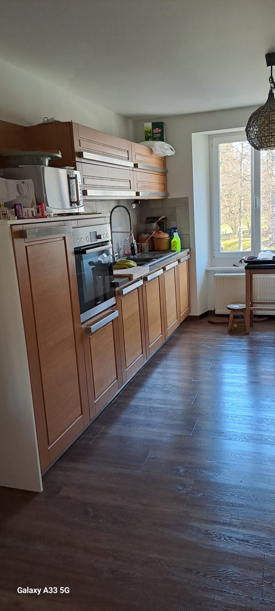 kitchen with wooden cabinets, oven, sink, window, wooden floor