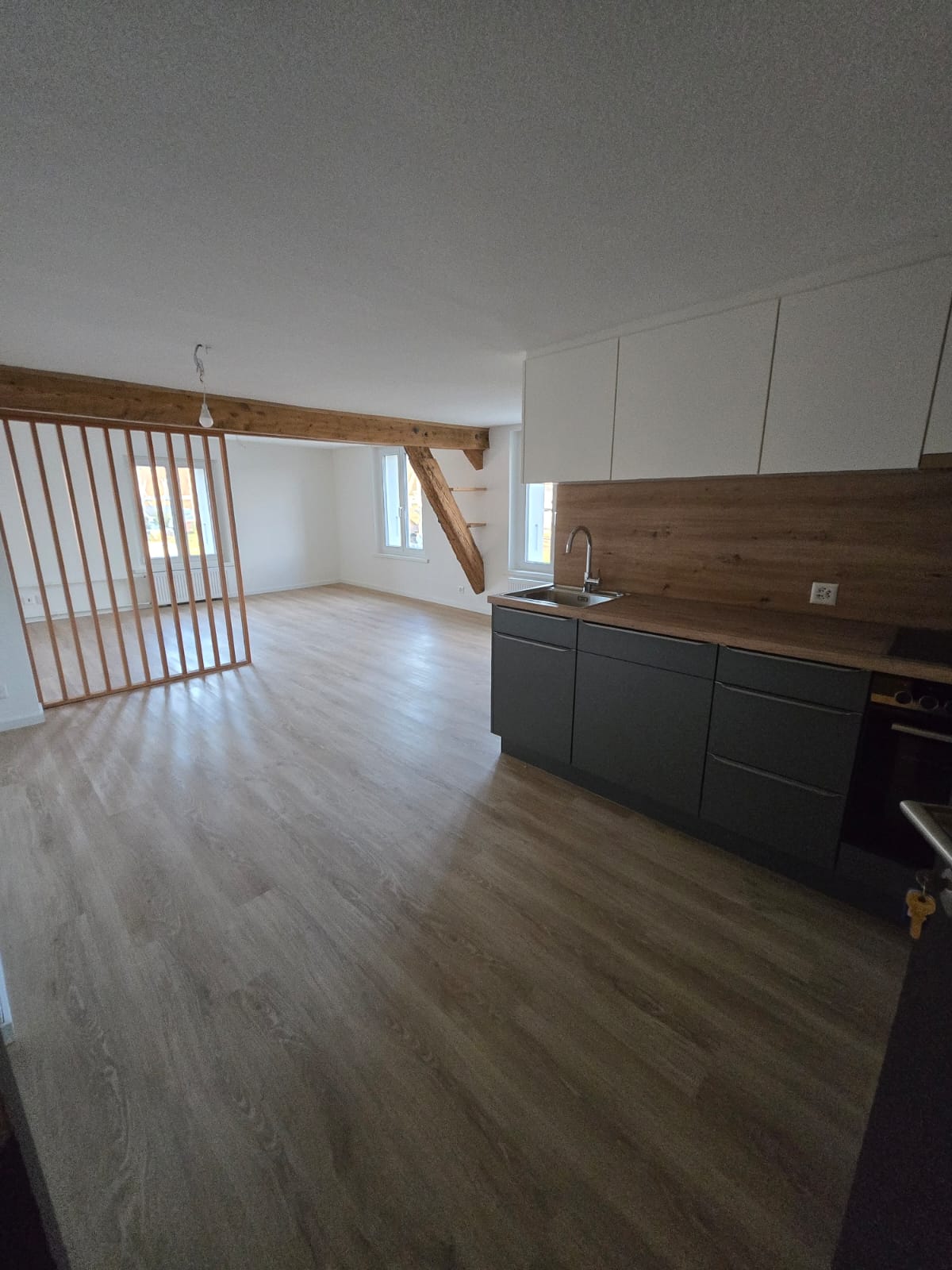 empty room with wooden floor, kitchen with cabinets, sink, faucet, wooden counter top, power outlet, sliding gate in the back