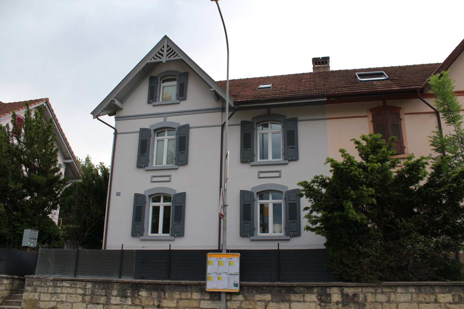 3 story house, white walls, gray shutters, brown roof, chimney, garden, fence, trees
