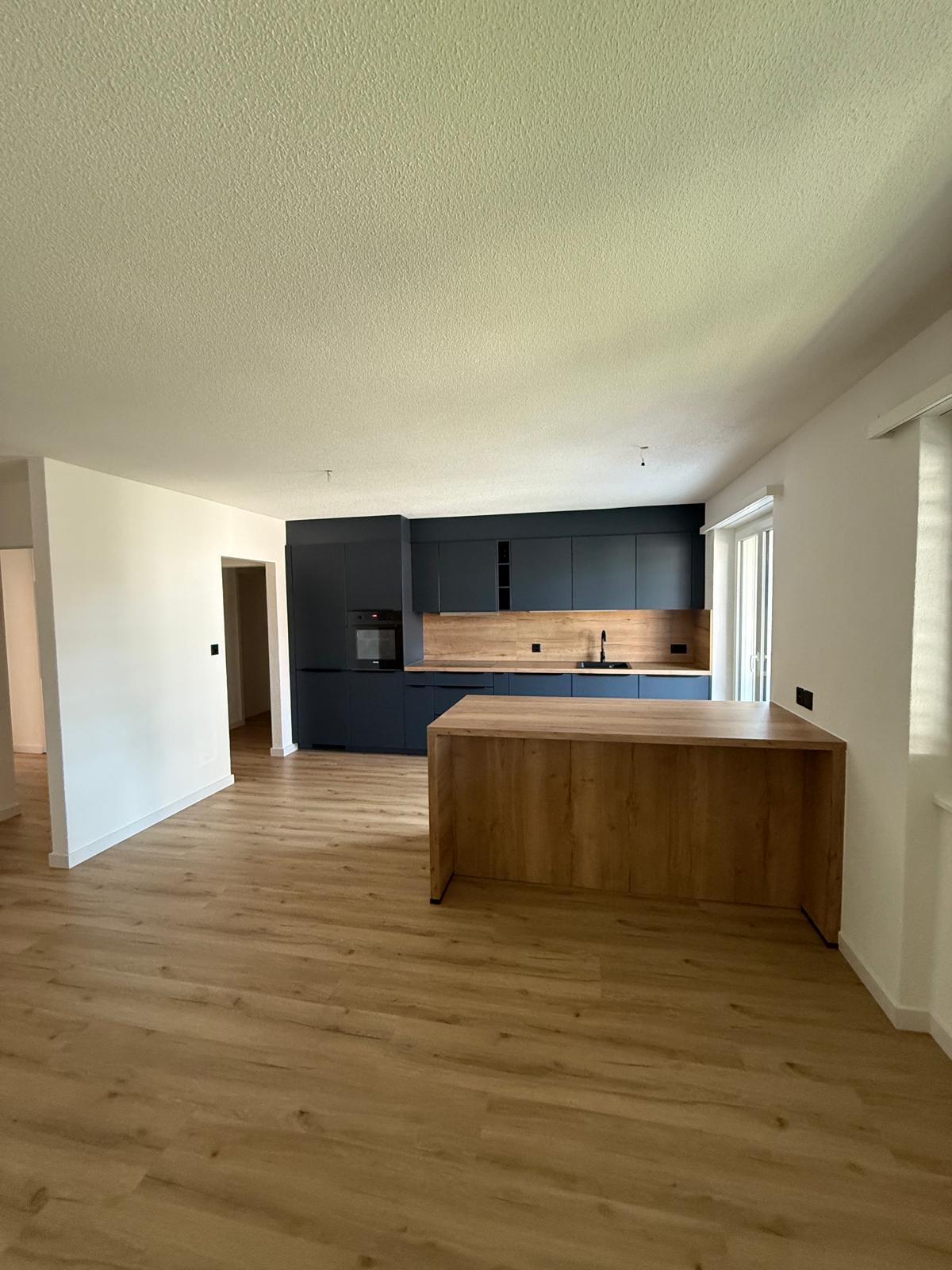 An empty kitchen with a wooden floor, modern cabinets, and a kitchen island.