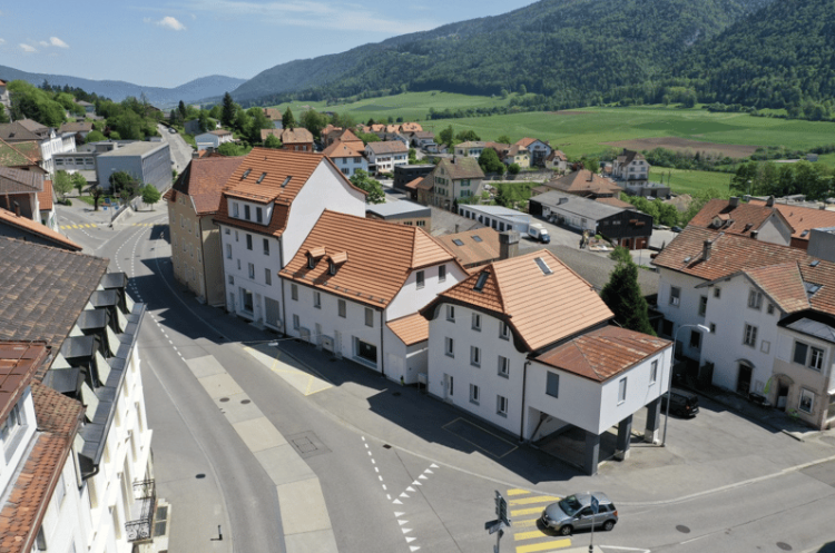 Aerial view of a residential area with several buildings, one of which has a raised ground floor.