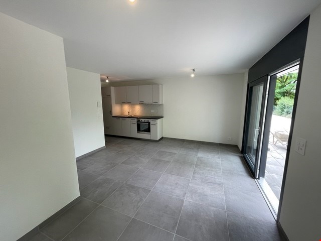 empty kitchen with gray floor, white cabinets, open sliding glass door, balcony with white door