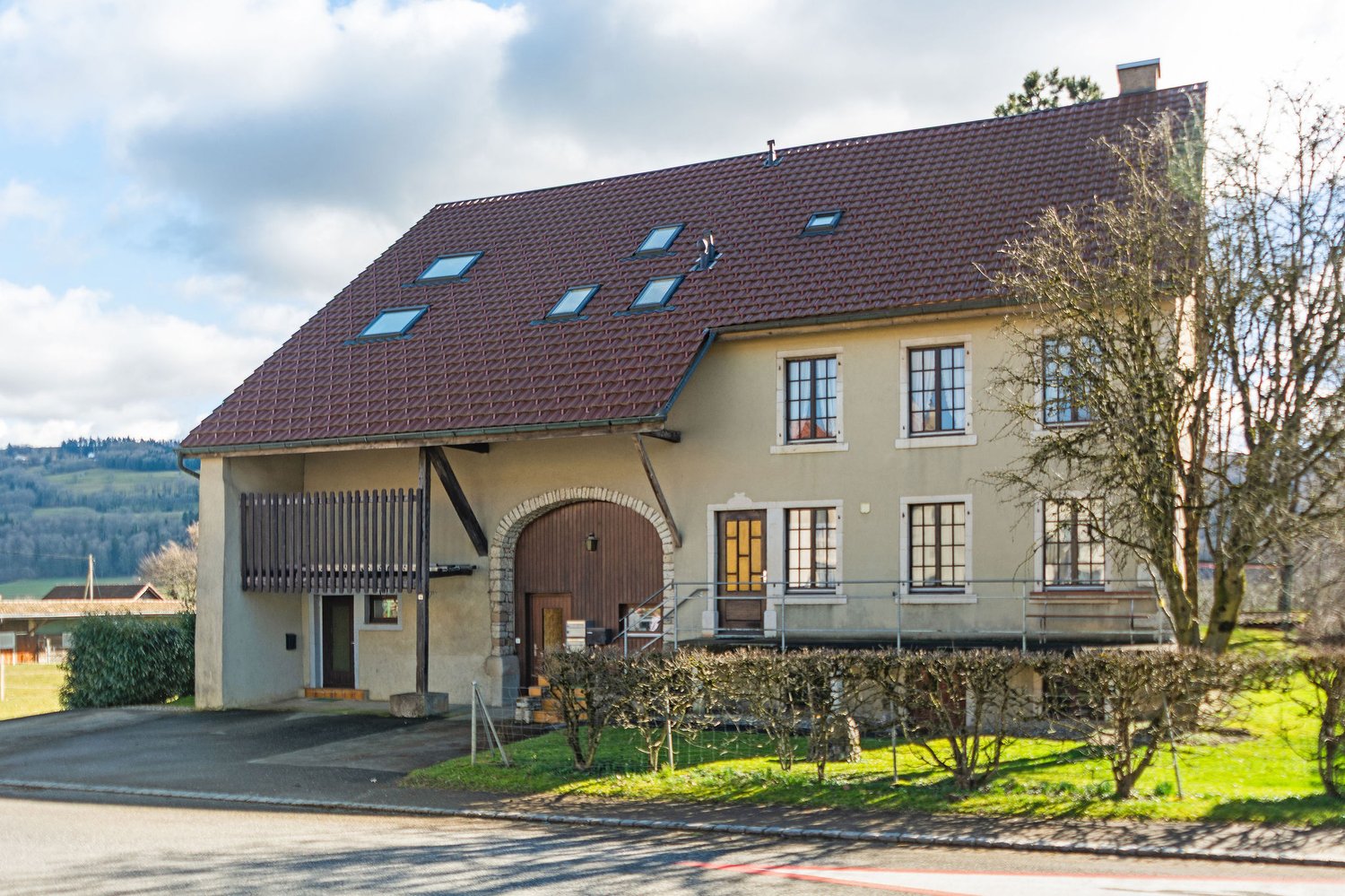 2 story house, brown roof, beige walls, wooden door, windows, balcony, driveway