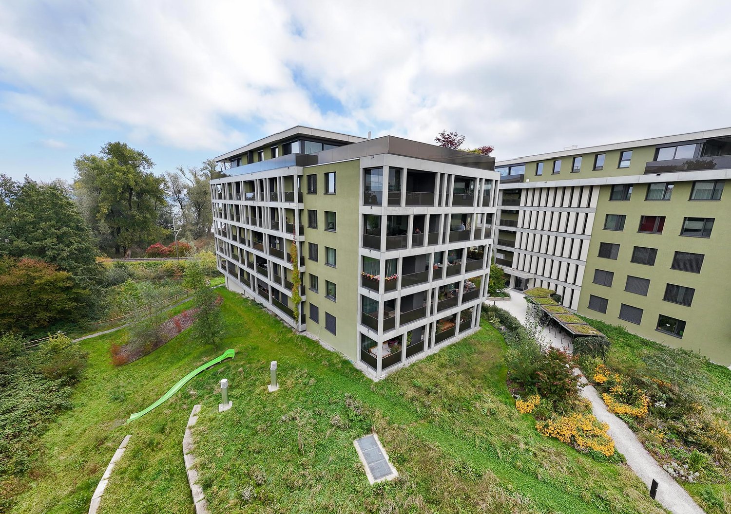 An apartment building, multiple floors, balconies, garden area, sliding slope