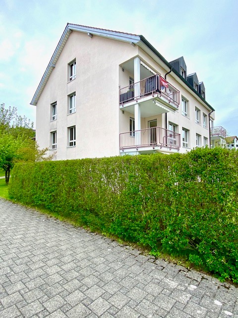 2 story building, balcony, paved pathway, bushes