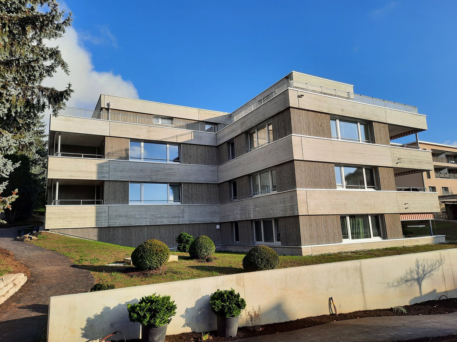 4 story apartment building, beige concrete, glass windows, roof terrace