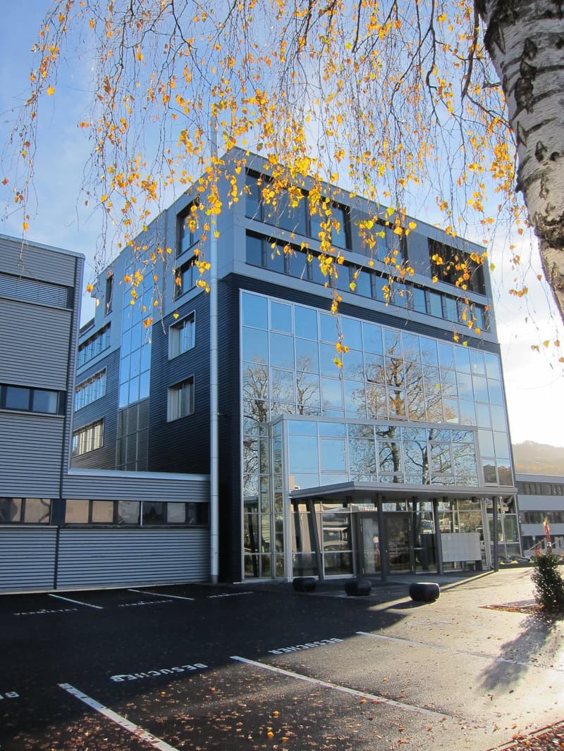 Modern office building, glass facade, black trim, 4 floors, parking lot in front