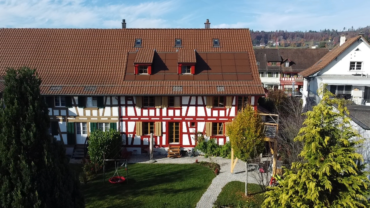 2 story house, brown roof, red and white facade, garden, play equipment