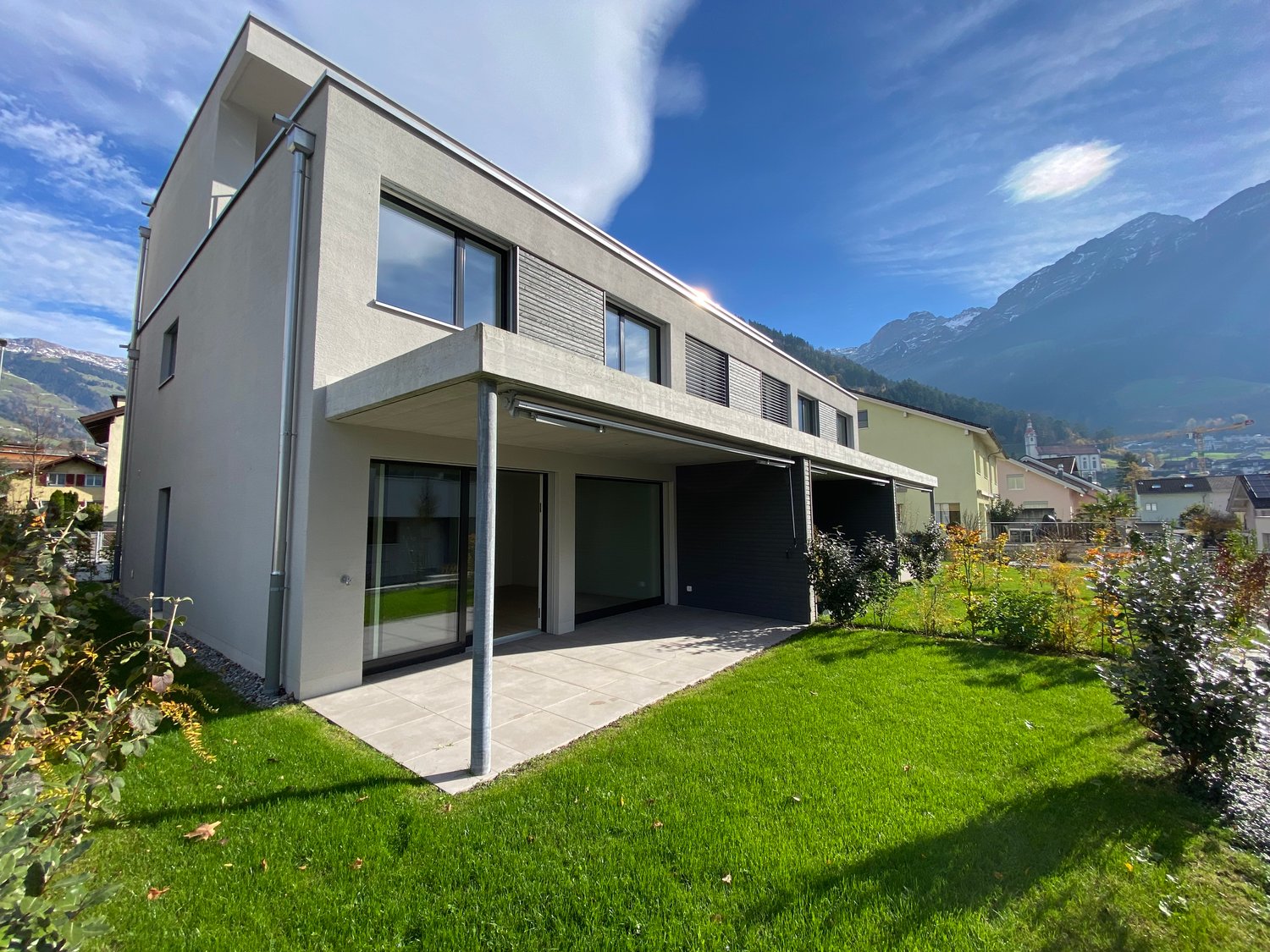 modern two-story house, large glass windows, concrete terrace, green lawn, mountain view