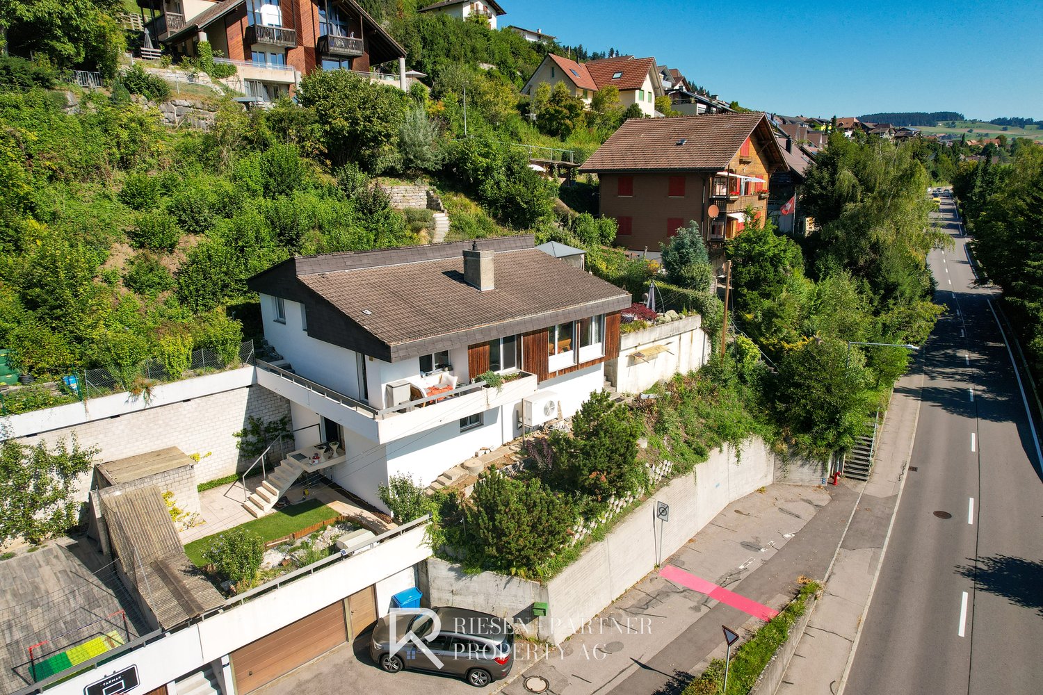 Detached house, raised ground floor, brown roof, white exterior, terrace, garden, garage