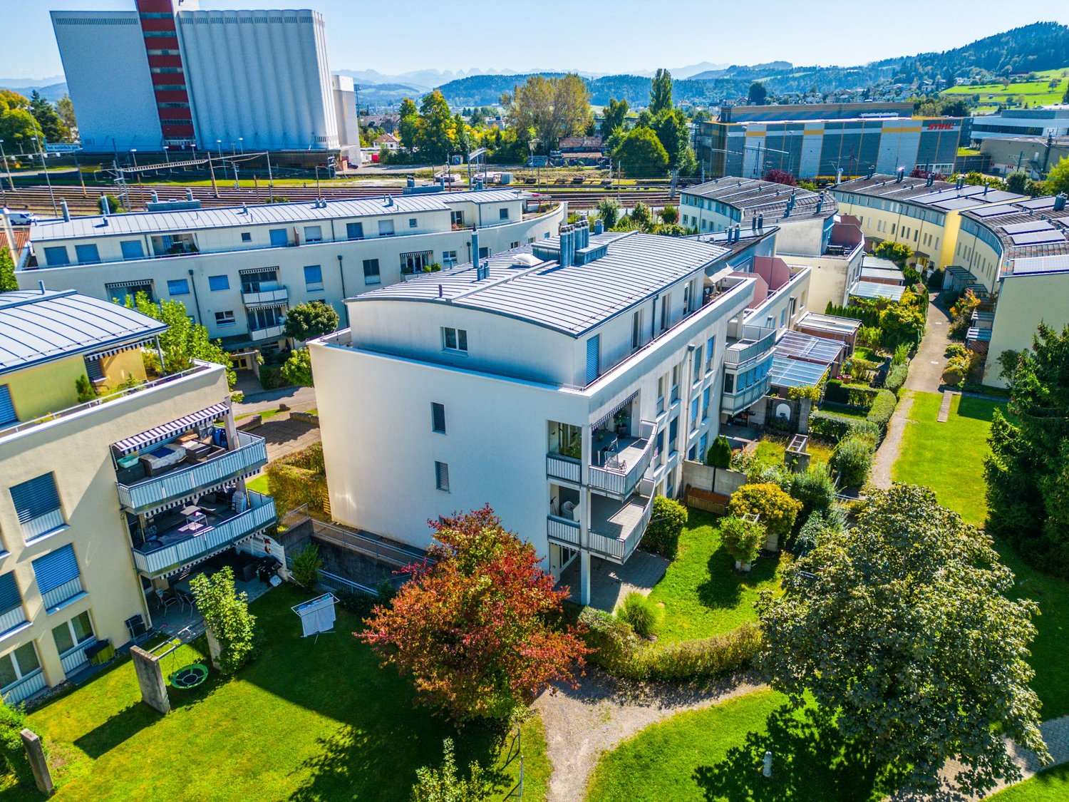 modern buildings, gray roofs, multiple balconies, green lawns, trees